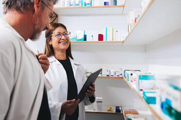 Male and female pharmacists working together in a chemist. Two mature healthcare professionals doing an inventory take in a pharmacy. - JLPSF28951