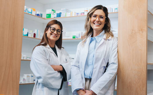 Apothekerinnen stehen in einer Apotheke und lächeln in die Kamera. Zwei medizinische Fachkräfte arbeiten zusammen in einer Apotheke. - JLPSF28972