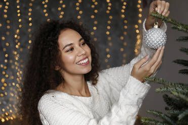 Glückliche schöne Frau schmückt Weihnachtsbaum zu Hause - SYEF00165