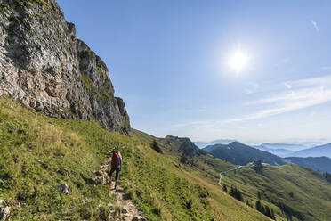 Germany, Bavaria, Sun shining over female hiker following trail to summit of Rotwand mountain - FOF13263