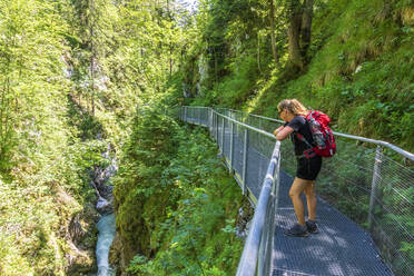 Austria, Female hiker admiring Leutascher Ache river flowing through Leutasch Gorge - FOF13301