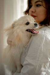 Schöne junge Frau mit Pomeranian Hund zu Hause - ANAF00748