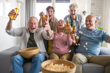 Gruppe von fröhlichen älteren Freunden beobachten Film drinnen, Party, geselliges Beisammensein und Spaß haben Konzept. - HPIF05353