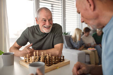 Gruppe glücklicher älterer Freunde, die drinnen Brettspiele spielen, Konzept für eine Party und ein geselliges Beisammensein. - HPIF05355