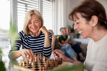 Group of happy senior friends playing board games indoors, party and social gathering concept. - HPIF05357