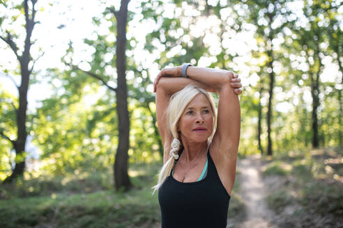 Ein Porträt von aktiven älteren Frau Läufer Stretching im Freien im Wald. - HPIF05400