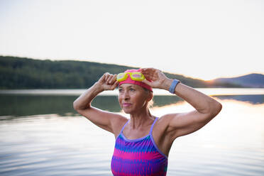 Ein Porträt einer aktiven älteren Frau, die im Freien am See schwimmt. - HPIF05415