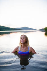 A portrait of active senior woman swimmer diving outdoors in lake. - HPIF05427