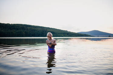 Ein Porträt einer aktiven älteren Schwimmerin, die im Freien in einem See steht und plantscht. - HPIF05431