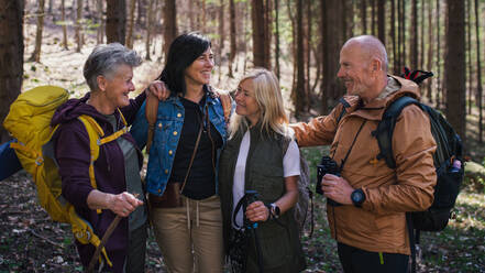 Porträt einer Gruppe von Senioren, die draußen im Wald in der Natur wandern und in die Kamera schauen. - HPIF05473