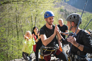 Eine Gruppe von Senioren mit einem Lehrer, die draußen in der Natur auf Felsen klettern und einen aktiven Lebensstil pflegen. - HPIF05487