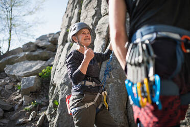 Ältere Frau mit nicht erkennbarem Lehrer, die draußen in der Natur auf Felsen klettert, aktiver Lebensstil. - HPIF05488