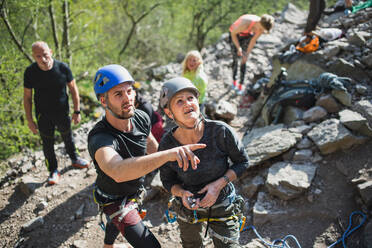 A group of seniors with instructor climbing rocks outdoors in nature, active lifestyle. - HPIF05493