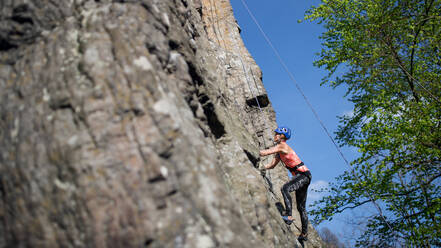 Mid adult woman climbing rocks outdoors in nature, an active lifestyle. - HPIF05499