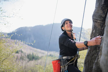 Porträt einer älteren Frau, die draußen in der Natur auf Felsen klettert, aktiver Lebensstil. - HPIF05503