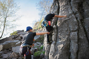 Porträt eines älteren Mannes mit Ausbilder, der draußen in der Natur auf Felsen klettert, aktiver Lebensstil. - HPIF05508