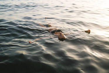 Frau schwimmt im Meer bei Sonnenuntergang - MMPF00576