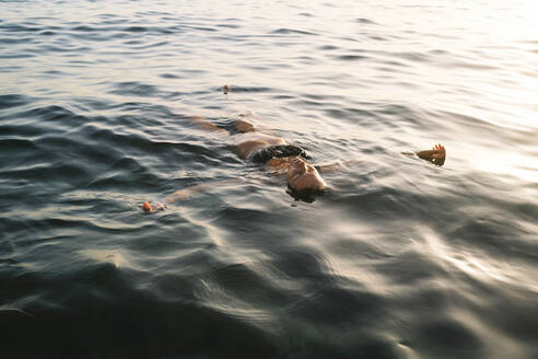 Frau schwimmt im Meer bei Sonnenuntergang - MMPF00576