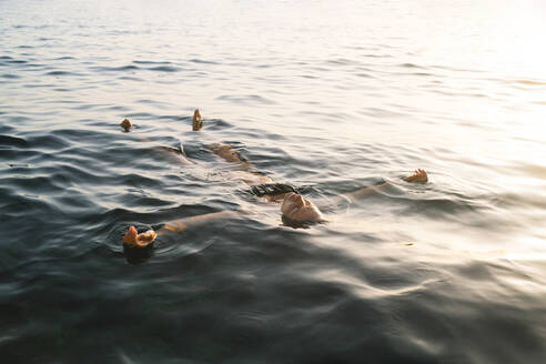 Frau schwimmt bei Sonnenuntergang auf dem Meer - MMPF00577