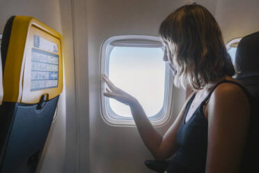 Frau schaut durch ein Flugzeugfenster - MMPF00579