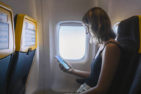 Frau benutzt Smartphone im Flugzeug - MMPF00580