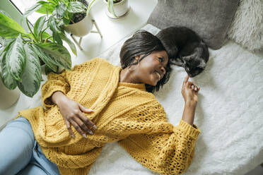 Lächelnde junge Frau liegt mit Katze zu Hause - OSF01246