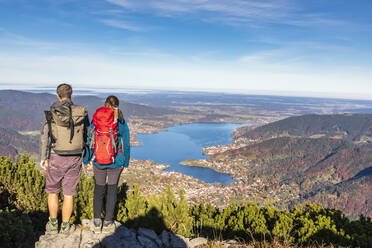 Germany, Bavaria, Rottach-Egern, Hiking couple admiring view of Lake Tegernsee and surrounding towns from summit of Wallberg mountain - FOF13314