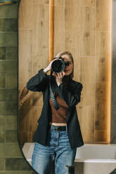 Woman photographing through camera seen in bathroom mirror - VSNF00215