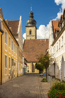 Deutschland, Bayern, Forchheim, Häuser entlang einer Kopfsteinpflastergasse mit der Kirche St. Martin im Hintergrund - TAMF03810