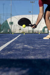 Hand eines jungen Mannes mit Schläger, der auf einem Sportplatz Paddle-Tennis spielt - FMOF01613