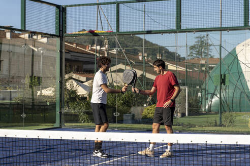 Freunde mit Tennisschlägern spielen auf dem Sportplatz - FMOF01615