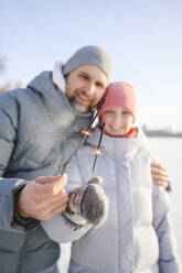 Glücklicher Vater und Tochter halten Wunderkerzen im Winter - EYAF02408