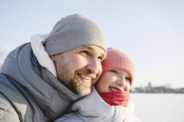 Glücklicher Vater und Tochter mit Strickmützen im Winter - EYAF02414