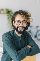 Happy freelancer with arms crossed sitting on chair in office - XLGF03140