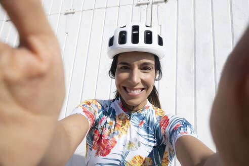 Glücklicher Radfahrer macht Selfie vor einer Mauer - JCMF02322