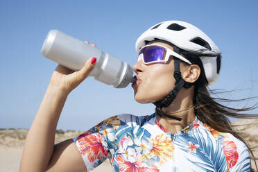 Durstiger Radfahrer trinkt Wasser unter dem Himmel - JCMF02331