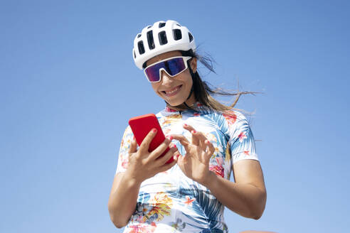 Glücklicher Radfahrer mit Smartphone unter freiem Himmel - JCMF02333