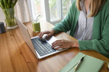 Freiberufler arbeitet am Laptop am Tisch in der Küche - SVKF00942