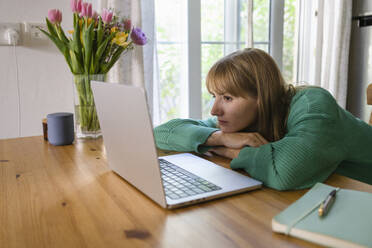 Freelancer with laptop leaning on table at home - SVKF00945