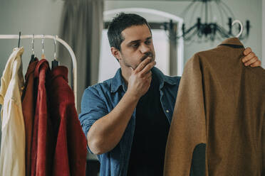 Man choosing clothes at home - VSNF00236