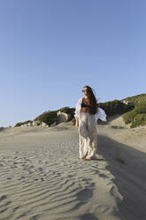 Young woman standing on sand at beach, Patara, Turkiye - SYEF00200