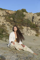 Nachdenkliche Frau mit langen Haaren am Strand sitzend, Patara, Turkiye - SYEF00206
