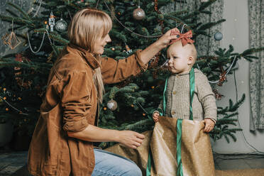 Glückliche Mutter spielt mit ihrem Sohn vor einem Weihnachtsbaum - VSNF00248