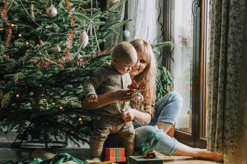 Glückliche Mutter spielt mit ihrem Sohn vor dem Weihnachtsbaum - VSNF00252