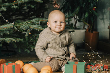 Lächelnde niedlichen kleinen Jungen sitzen mit Orangen und Geschenk-Boxen zu Hause - VSNF00255