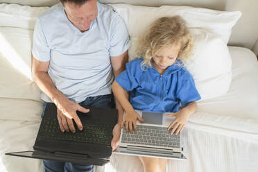 Mädchen und Mann benutzen Laptops auf dem Bett zu Hause - SVKF00999