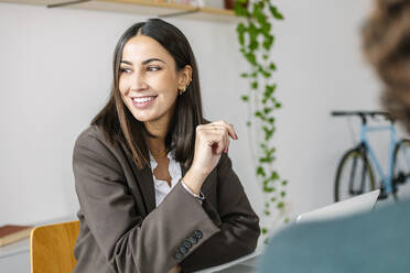 Smiling businesswoman by colleague at desk in office - XLGF03165