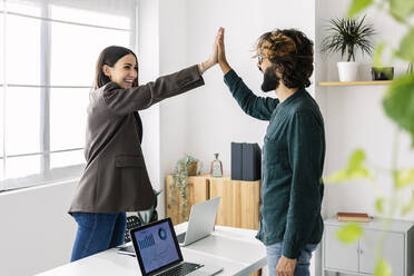 Glückliche Geschäftsfrau, die einem Kollegen im Büro die Hand drückt - XLGF03182