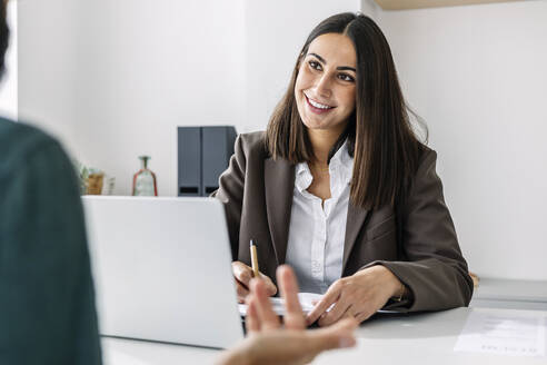 Smiling recruiter taking candidate's interview at desk - XLGF03228