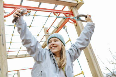 Lächelndes Teenager-Mädchen spielt auf einem Spielplatz unter dem Himmel - MDOF00448